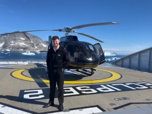 Adam Couzens deck cadet in front of a helicopter on a helipad 